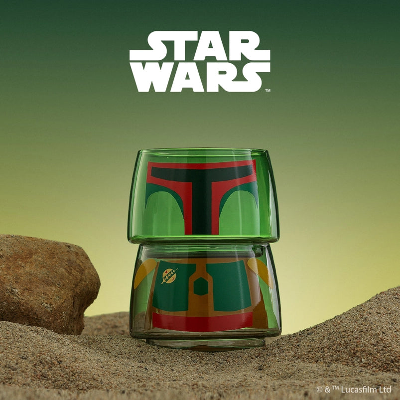 Two small drinking glasses stacked on each other on a stretch of sand, with a green background behind them. The two glasses combined depict the character Boba Fett from the Star Wars movies. White text at the top says "Star Wars."