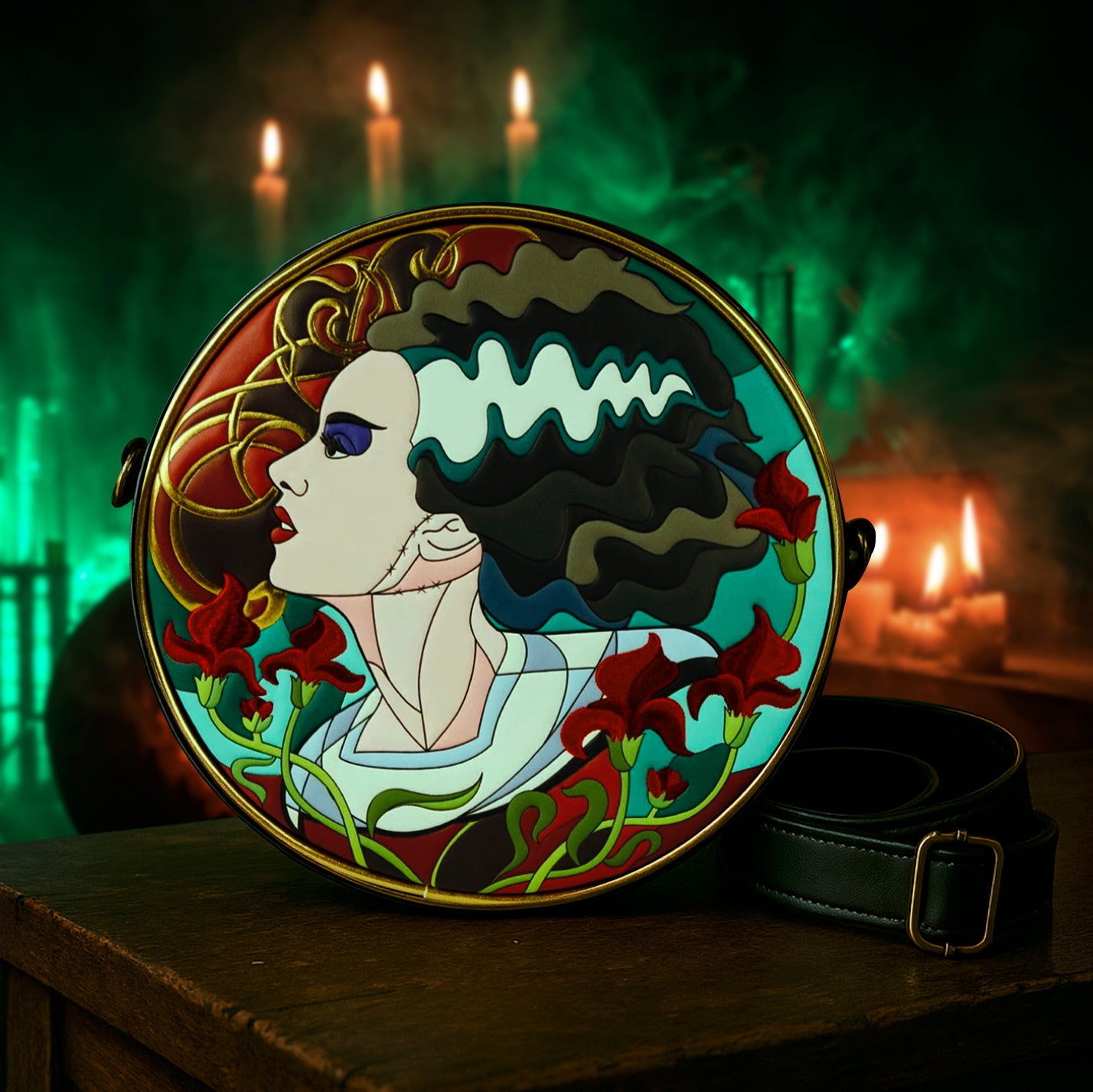 A round crossbody style purse with a black strap. The front of the bag has an image of the classic Bride of Frankenstein, portrayed in a stained glass style. In the background is a spooky lab with candles and green smoke.