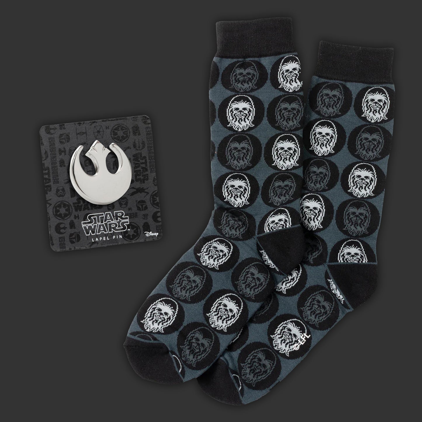 Black and grey socks with white Chewbacca pattern on a dark background. Next to the socks is a Rebel Alliance lapel pin
