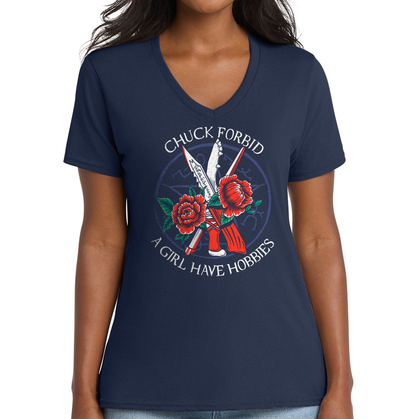 A woman wearing a navy blue V-neck t-shirt with a graphic on the front. The graphic features the text 'CHUCK FORBID' and 'A GIRL HAVE HOBBIES' in white around a central illustration of red roses, a red-and-white striped object, and two crossed white knives with red details.