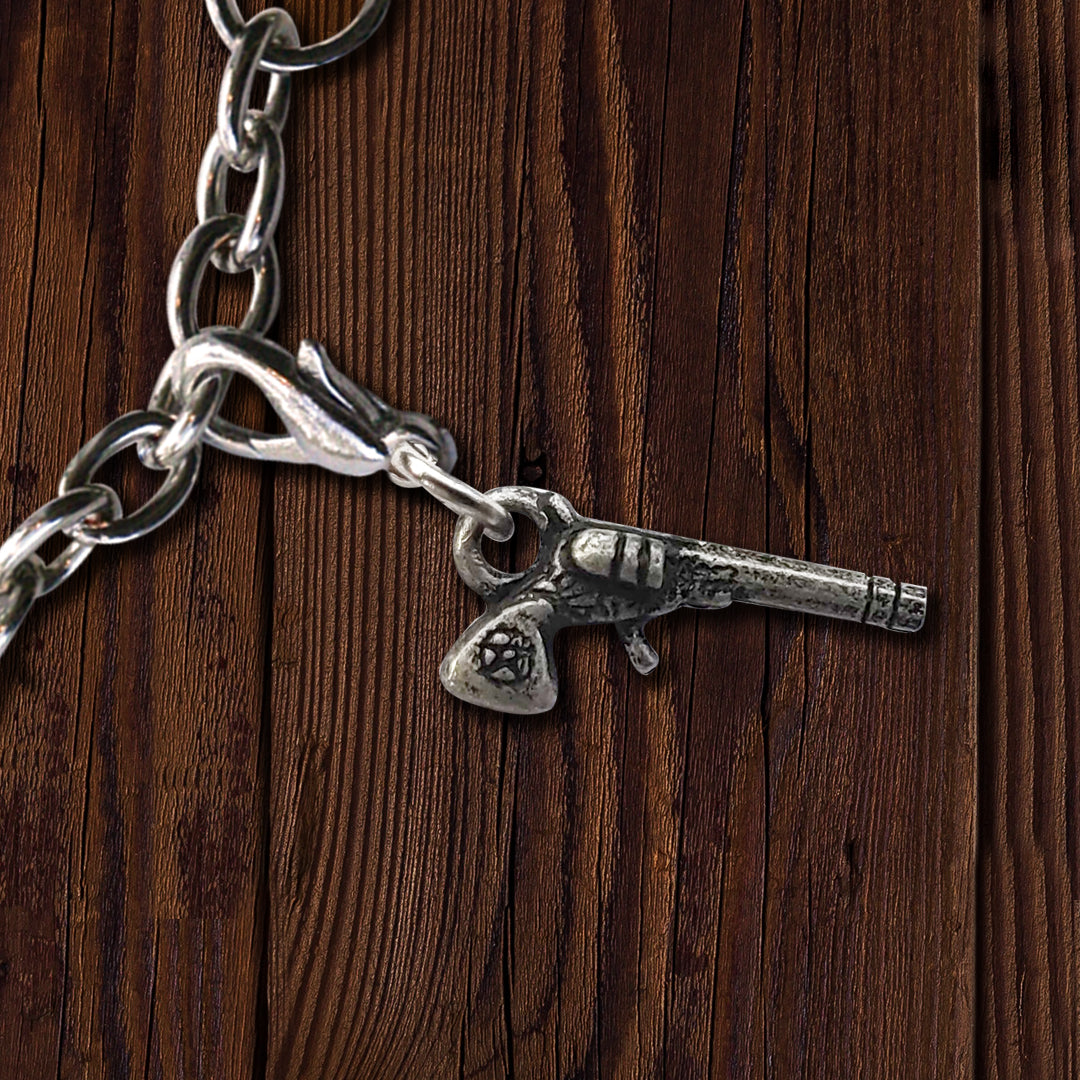 A brass charm in the shape of an old-fashion Colt revolver, on a dark wood background.