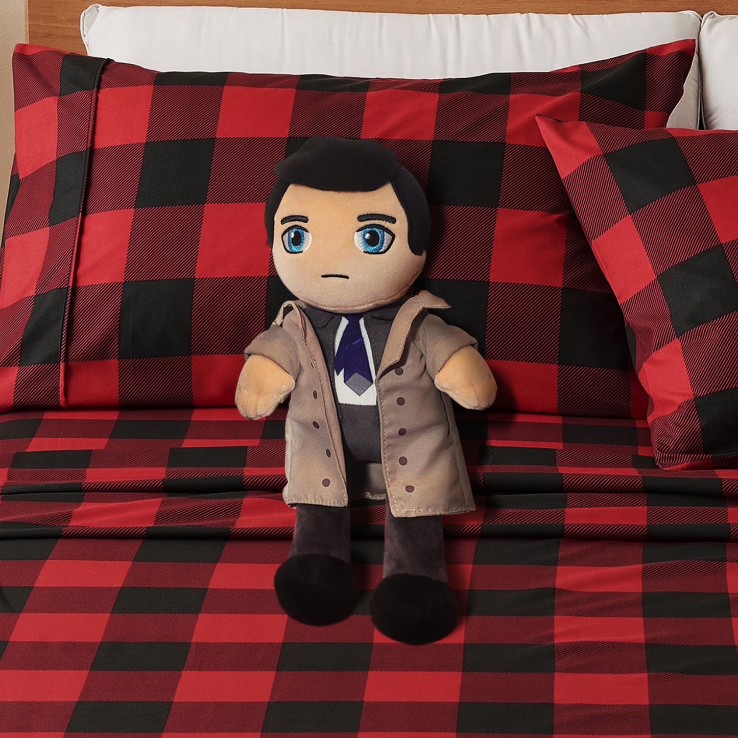 Plush toy resembling a character in a trench coat on a red and black checkered blanket