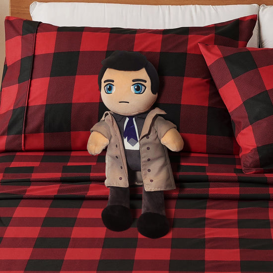 Plush toy resembling a character in a trench coat on a red and black checkered blanket