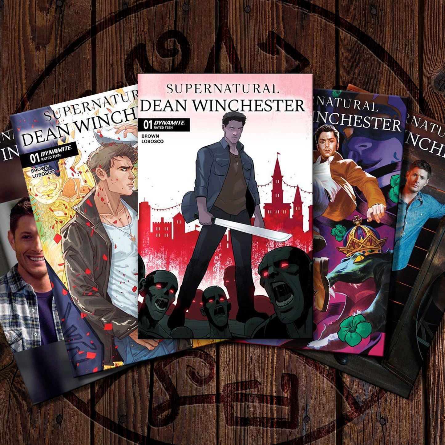 A fan arrangement of illustrated comic book covers for 'Supernatural: Dean Winchester' on a dark wood background. The visible covers show stylized artwork with red, black, pink, blue, and yellow tones, and the title 'Supernatural' and 'Dean Winchester' are clearly readable.