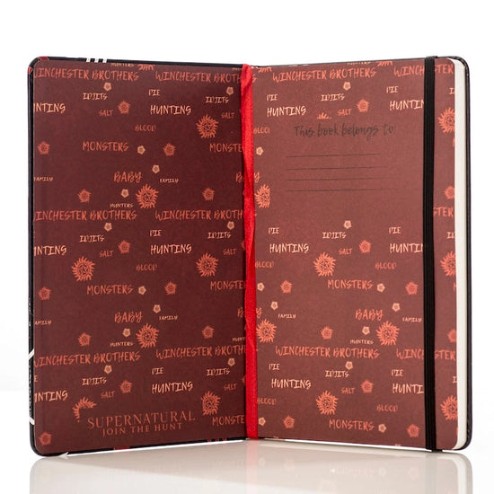 The inside cover of the journal. The pages are red, and have pink and yellow text scattered around with phrases and symbols from the series Supernatural.