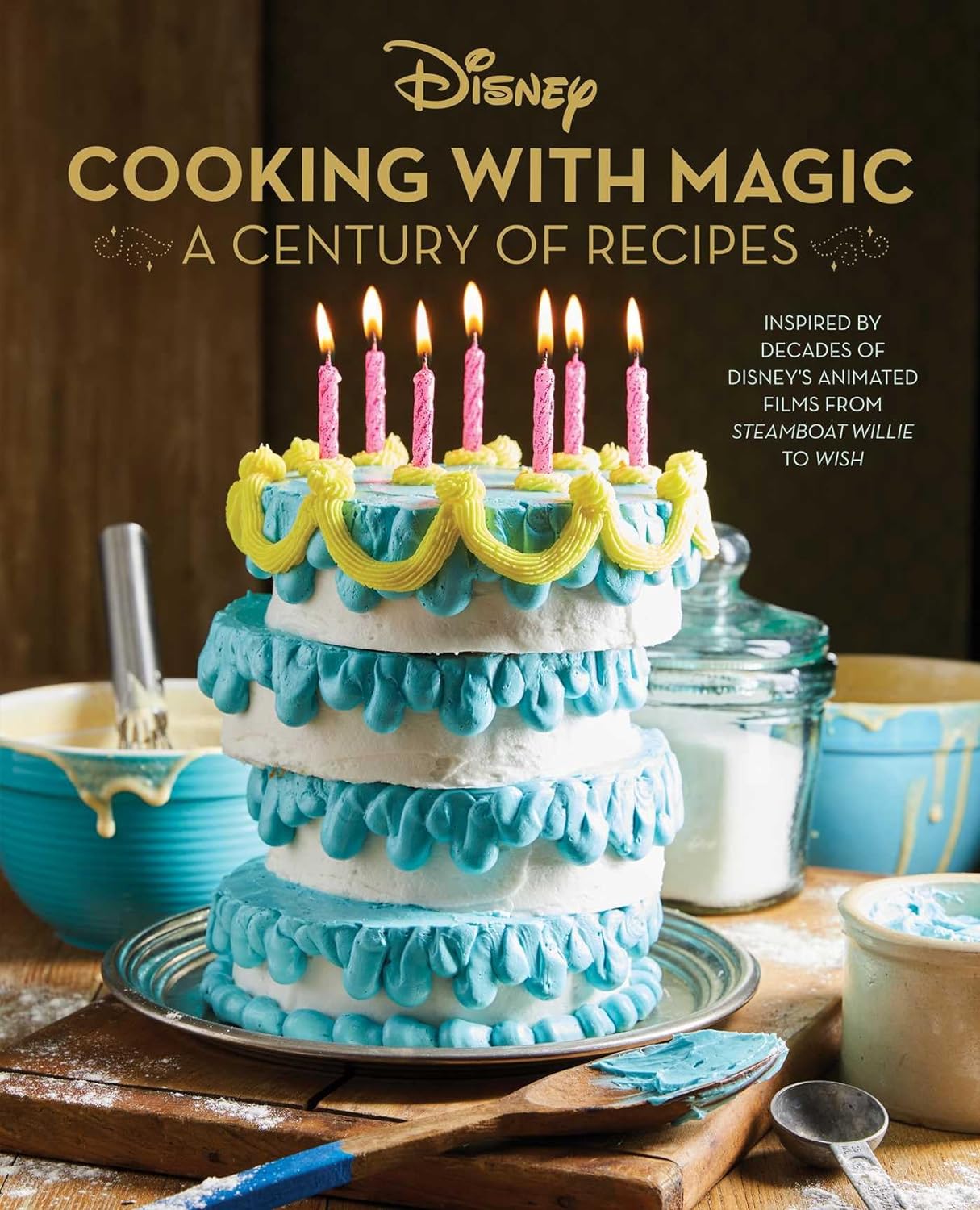 A brown cookbook cover with the Disney logo and the text: "COOKING WITH MAGIC: A CENTURY OF RECIPES" and "Inspired by decades of Disney's animated films from STEAMBOAT WILLIE to WISH". There is a blue, yellow, and white cake on the front with pink candles, surrounded by various baking tools.  