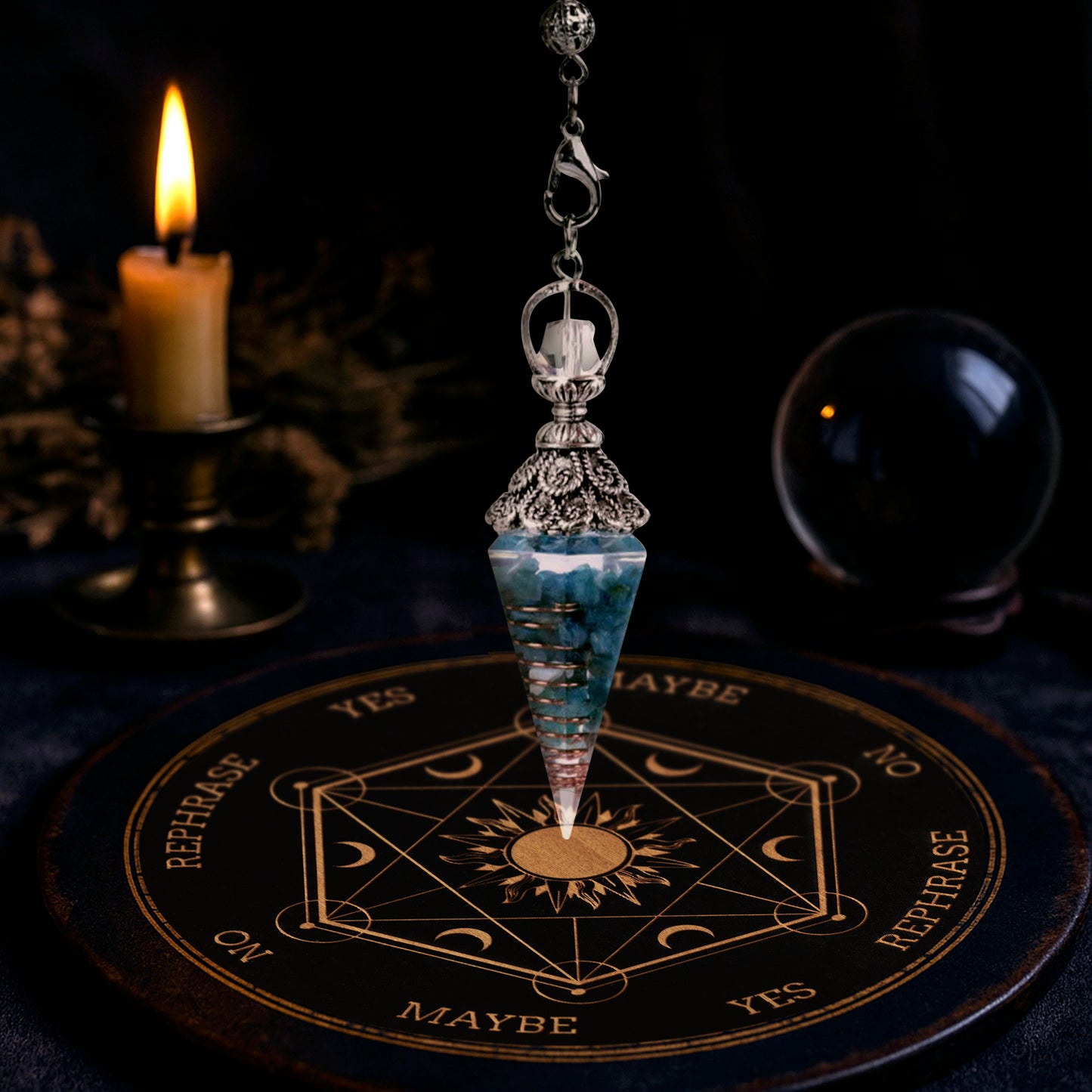 A cone-shaped blue crystal pendulum on a silver chain, hanging over an oracle plate on a table. In the background are a burning candle and a crystal ball.