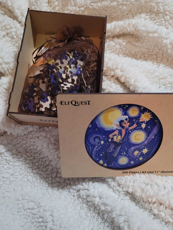 A wooden box on a white fuzzy blanket, open to show puzzle pieces inside. In the center is an image depicting the ElfQuest character Skywise in the sky, gathering stars.