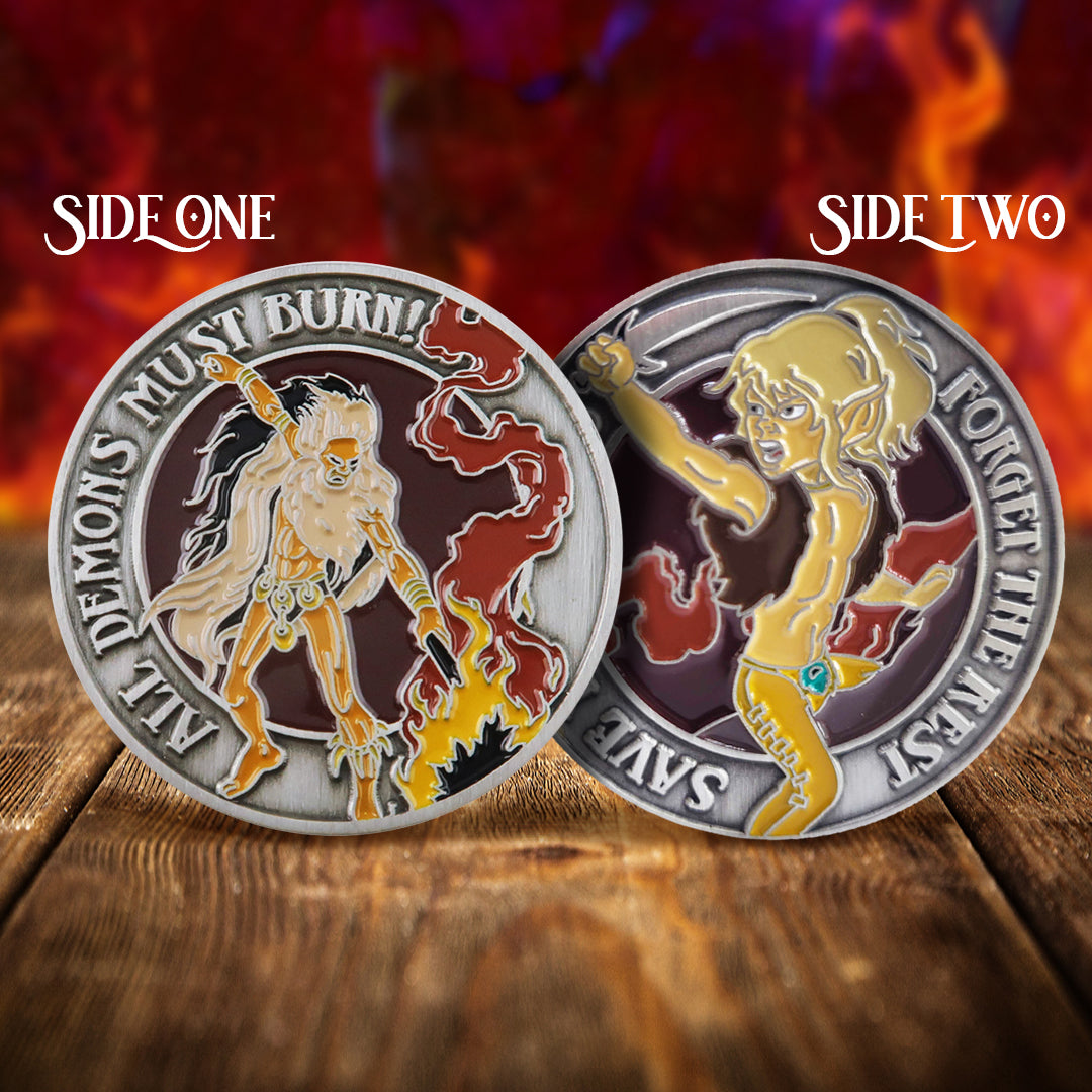 A front and back image of a brass challenge coin, on a wood table. On the front is a drawing of the Elfquest character Leetah. Raised text around the edge says “all demons must burn.” The back of the coin depicts the characters Nightfall and Redlance. Around the edge, raised text says “Save your lives, forget the rest." Behind the coin is a fiery red background.