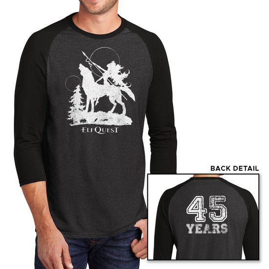 Two images of a male model wearing a grey long sleeve T-shirt with black sleeves. The larger image has a white image of an elf riding on the back of a large howling wolf, next to a small tree. The elf is holding a spear, and pointing it toward the sky. Under the wolf is text saying "ELFQUEST." The smaller image shows the back of the shirt, with "45 Years" printed in large white text.