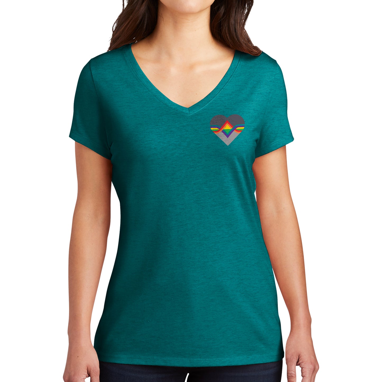A female model wearing a teal T-shirt. The Acting Ensign Pride symbol is at the top left corner of the shirt.  The symbol is a grey heart with rainbow lines running through the center.