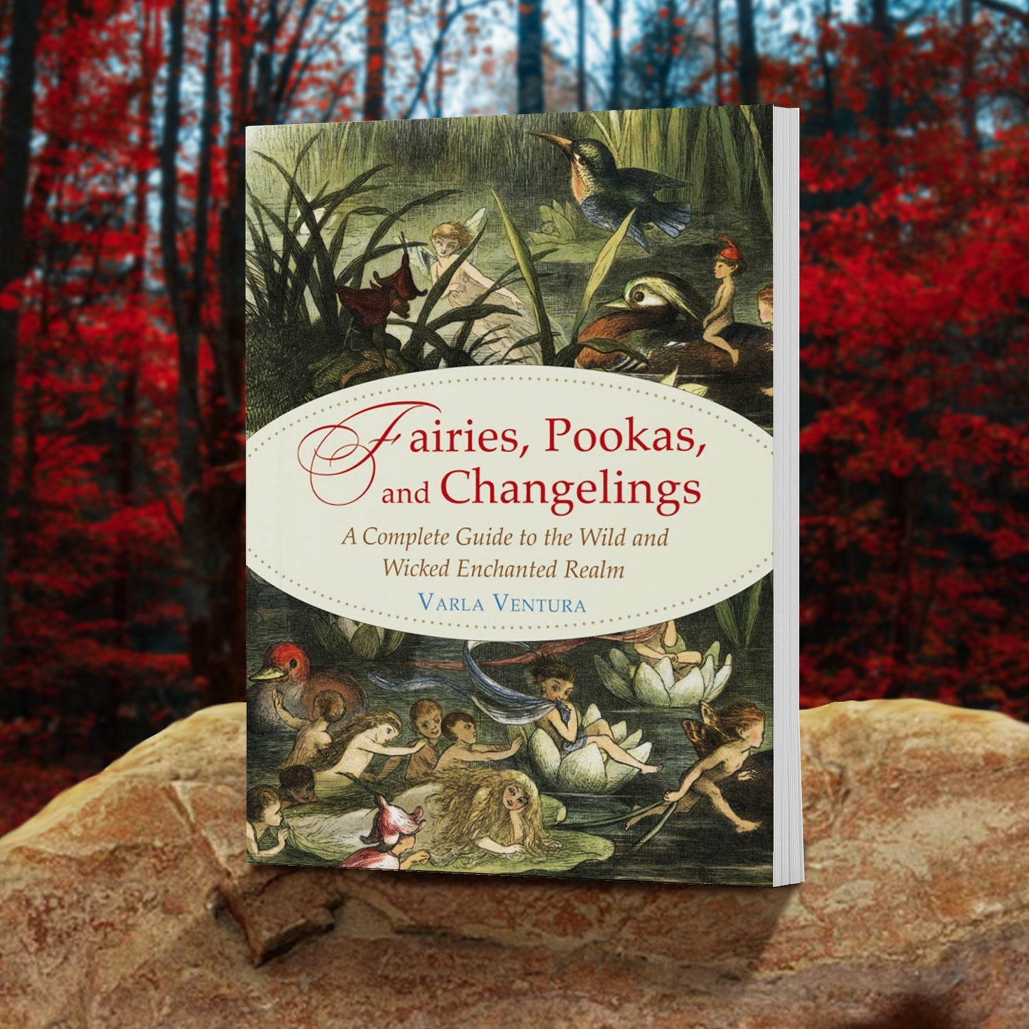 A green book on a rock, against a background of red-leaved trees. On the cover is a drawing of a marsh, with tall grass and lily pads. Scattered around the marsh are various fairies and other small mythical creatures, alongside birds. At the center of the cover is a white oval. In the oval is red and tan text saying "Fairies, pookas, and changelings: a complete guide to the wild and wicked enchanted realm.