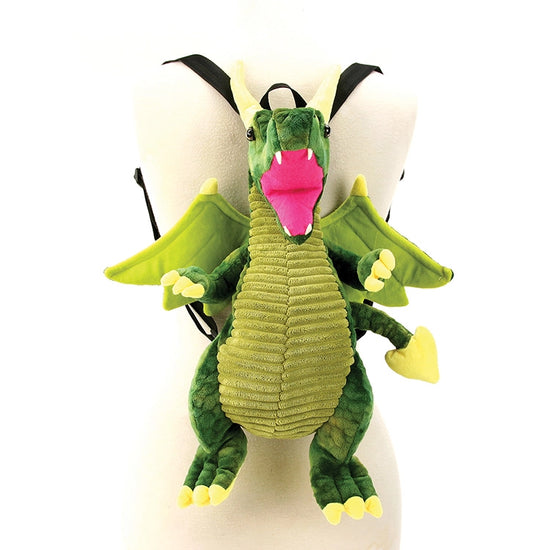 A dragon-shaped backpack in shades of green, hanging on a white mannequin. The dragon has green wings, and a red mouth, with black straps at the back.