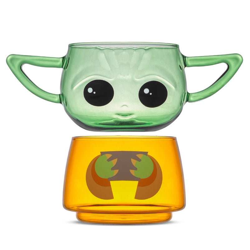 Two small drinking glasses stacked on each other against a white background. The two glasses combined depict the character Grogu from the Star Wars series The Mandalorian. The top glass has two handles shaped as his ears. The two glasses are slightly separated from each other.