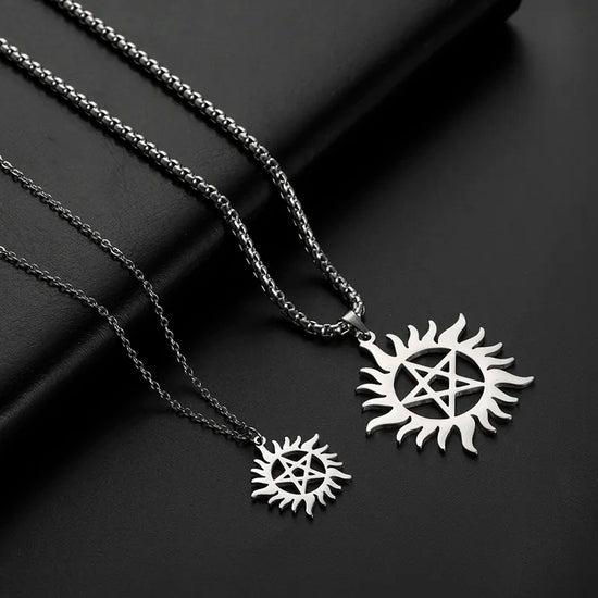 Two necklaces, side by side, on a black leather background. Both necklaces have pendants in the form of the Anti-Possession symbol. The pendant on the left is smaller than the pendant on the right.