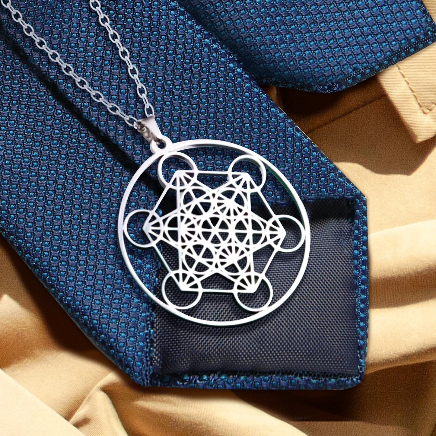 A silver pendant on a blue necktie and tan trench coat. The necklace depicts Metatron's cube, set in a circle. A silver chain is attached to the top of the pendant.