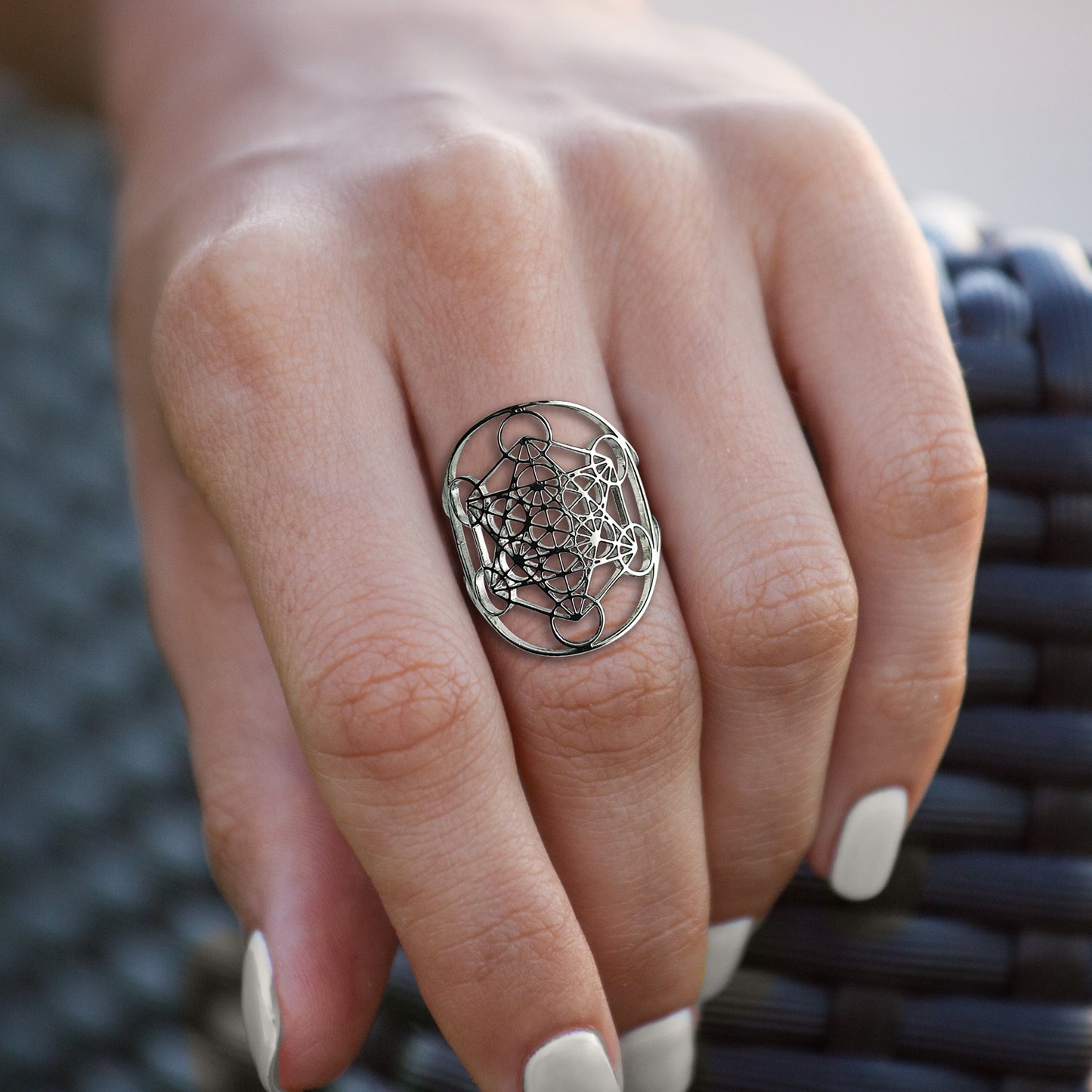 A silver ring on a model's finger. The ring depicts Metatron's Cube, a symbol consisting of 13 circles connected by straight lines.