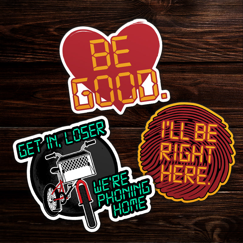 Three colorful stickers with text on a wooden background