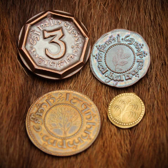 A set of four copper coins from The Hobbit, sitting on a pile of light brown straw. Around the edges of each coin are stamped symbols, taken from the Hobbit language in the Lord of the Rings series.