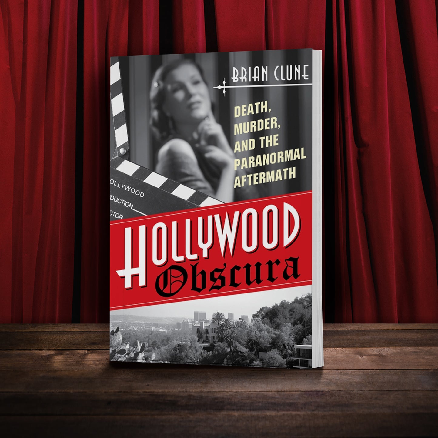 A black and white book on a stage, against a red curtain. On the cover is a blurred image of a Hollywood star at the top, and a view of old Hollywood at the bootom. In the center is a red banner, with "Hollywood Obscura" in white and black text.