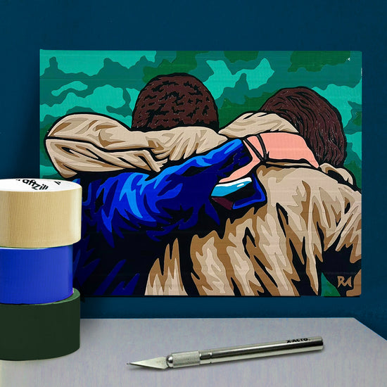 A poster made of layered pieces of duct tape, depicting a rear view of Sam and Dean Winchester with an arm around each other's back. In front of the poster is an X-acto knife and rolls of duct tape.