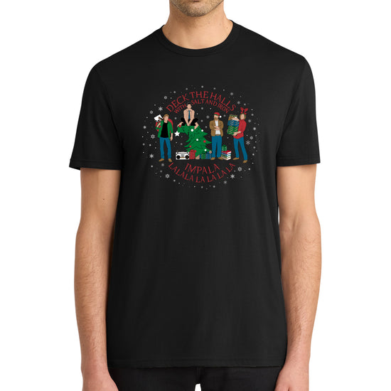 A model in a black tee shirt, with a Supernatural themed holiday design on the front. Red text says "deck the halls with salt and iron. Impala lalala la la lala."