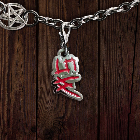 A metal charm on a linked bracelet, against a dark wooden background. The charm depicts the initials SW in red. At the top left is a charm with the anti-possession symbol at its center.