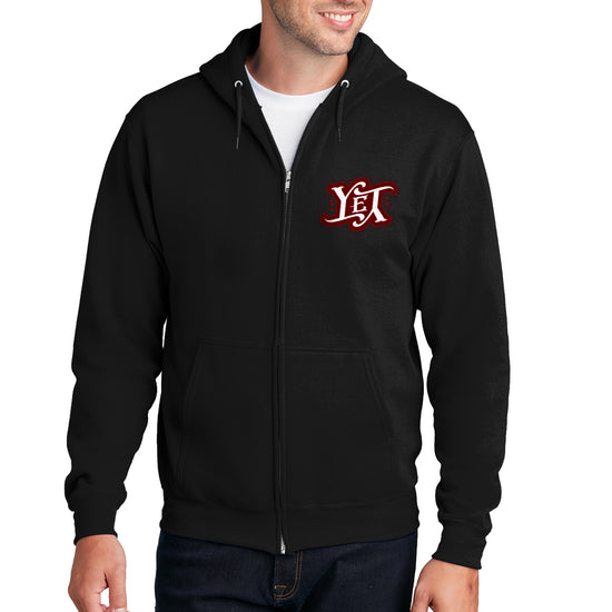 A male model wearing a black zippered pullover sweatshirt. On the left side are the letters YET in white, outlined in red. The letters are designed to spell the word "yet" right side up and upside down. 