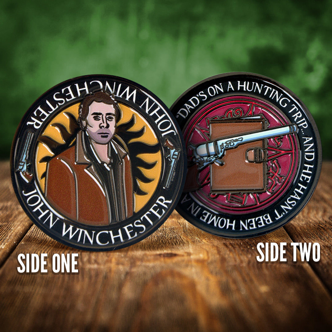 Front and back images of a challenge coin, side by side, on a wood table. The front depicts a drawing of John Winchester, wearing a brown jacket. Behind him is the edge of the anti-possession symbol. The back of the coin depicts a colt revolver on a brown journal, against a red background. White text around the edge says "Dad's on a hunting trip... and he hasn't been home in a few days"