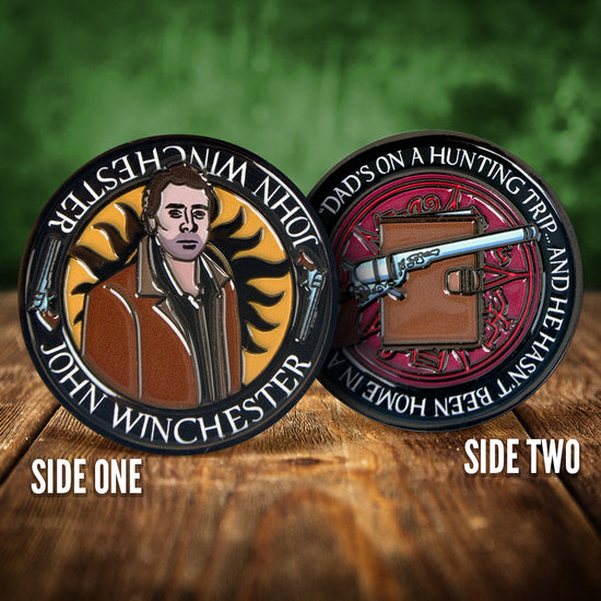 Front and back images of a challenge coin, side by side, on a wood table. The front depicts a drawing of John Winchester, wearing a brown jacket. Behind him is the edge of the anti-possession symbol. The back of the coin depicts a colt revolver on a brown journal, against a red background. White text around the edge says "Dad's on a hunting trip... and he hasn't been home in a few days"