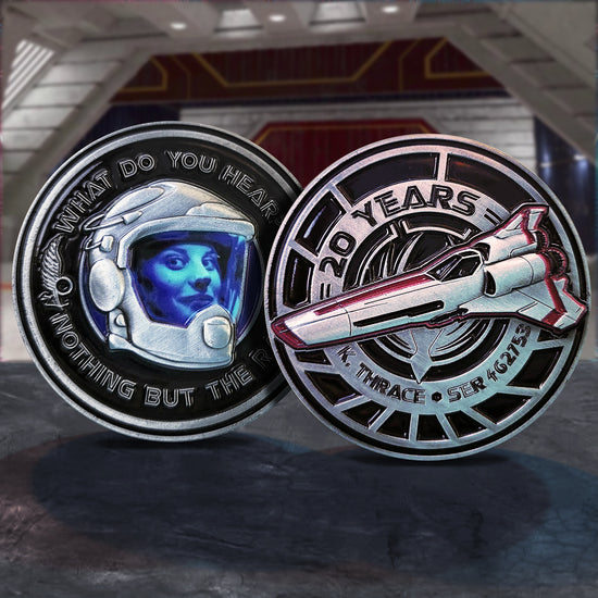 Side by side images of a metal challenge coin, on a dark grey table. The left coin depicts the character Starbuck in her flight helmet. Text around the edges says "what do you hear? nothing but the rain." The right coin depicts Starbuck's viper fighter ship, with black text that says "20 years, K. Thrace SER 4G2753"