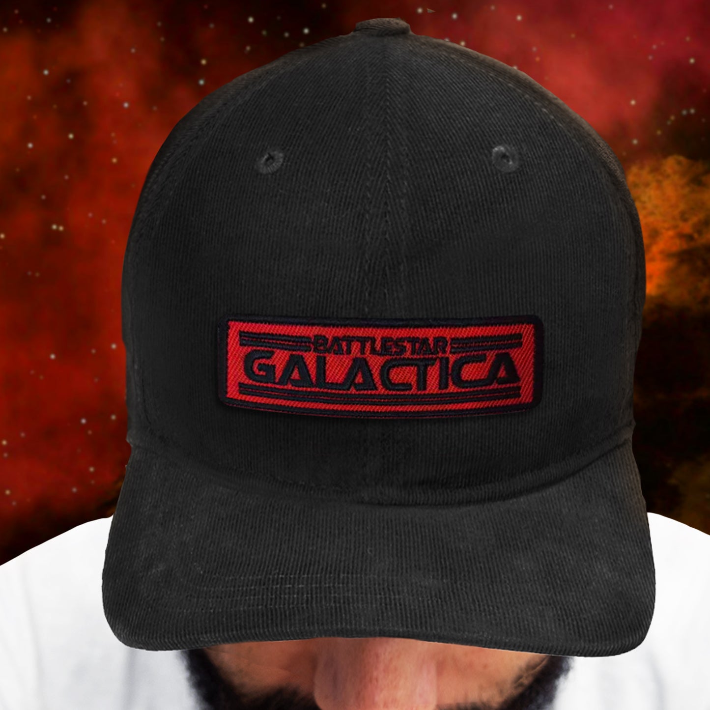 Black cap with 'Battlestar Galactica' logo worn by a person against a red and orange background