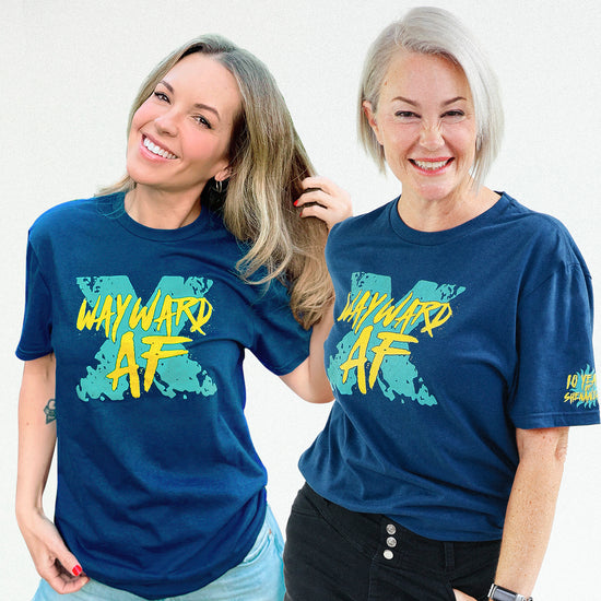 An image of actors Briana Buckmaster and Kim Rhodes, each wearing a blue tee shirt. On the front of each shirt is a large, light blue distressed X. On top of the X is yellow text that says Wayward AF. 