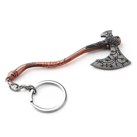 A key chain shaped like Leviathan Axe used by Kratos in the God of War video game series, against a white background. The axe handle is a dark rose gold color, with an S-shaped curve, and a key ring attached at the end. The axe head is dark grey with runes carved into the blade. A blue jewel sits in the center of the axe head.