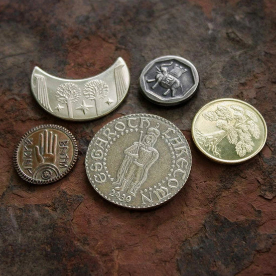 A set of five coins from the Lord of the Rings, sitting on a brown stone table. The coins depict various elements from the Lord of the Rings stories.