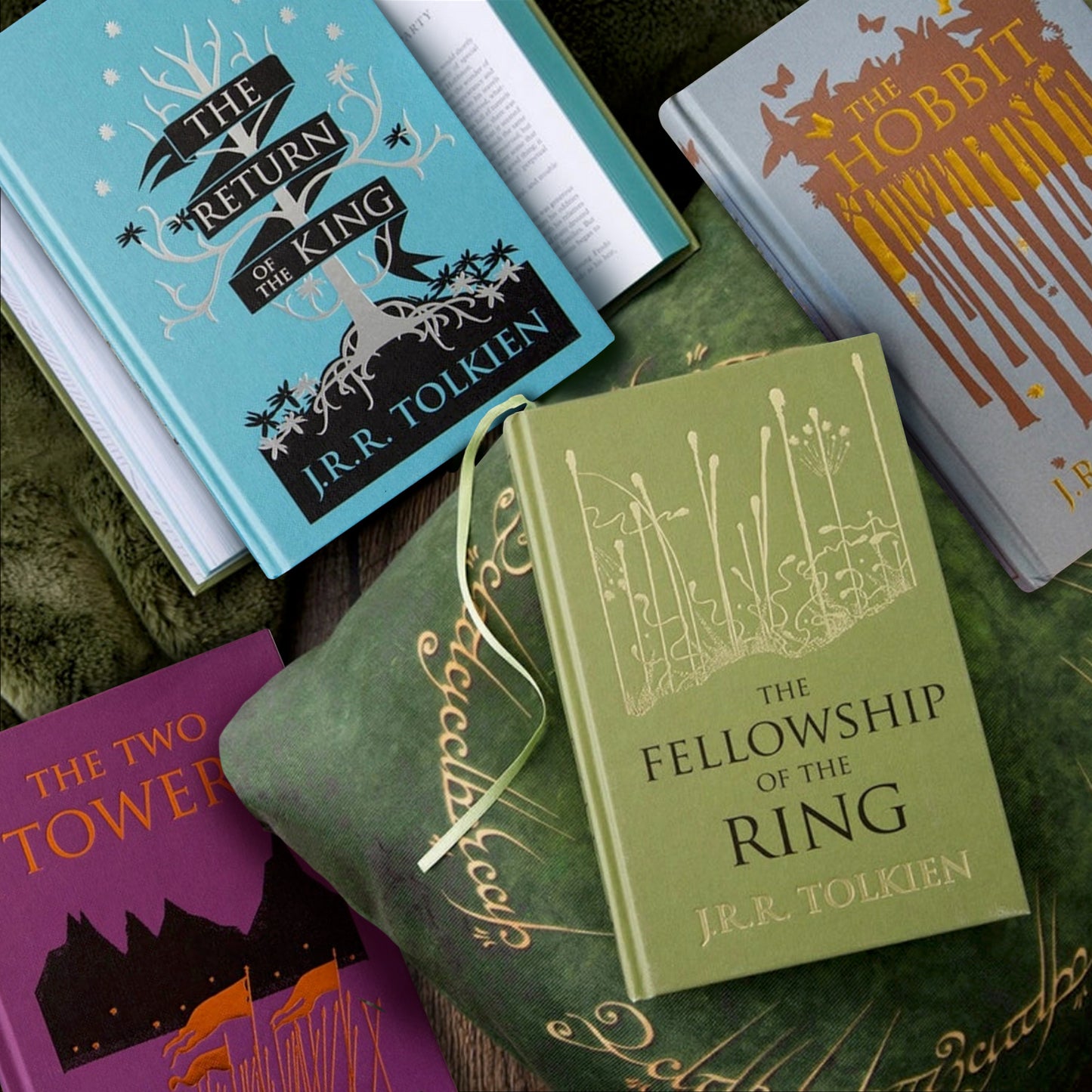 Hardcover copies of The Hobbit and the three Lord of The Rings books resting on pillows and rugs. 