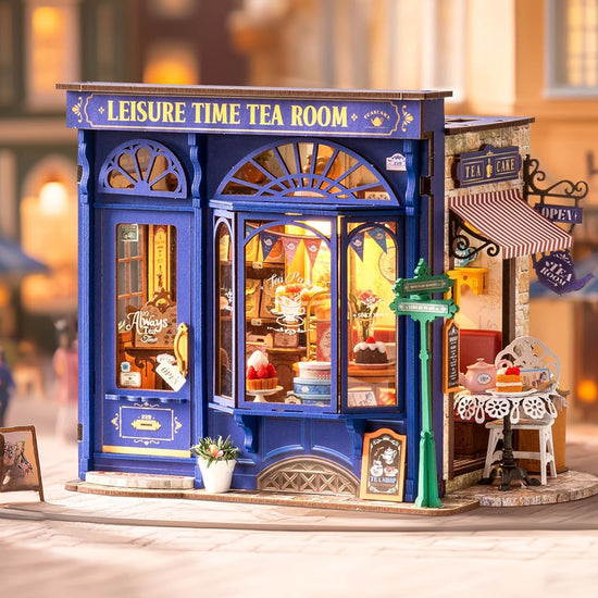 A blue miniature tea shop model kit in a small town setting. The interior features cakes, cups, and other decorations themed around a tea shop.