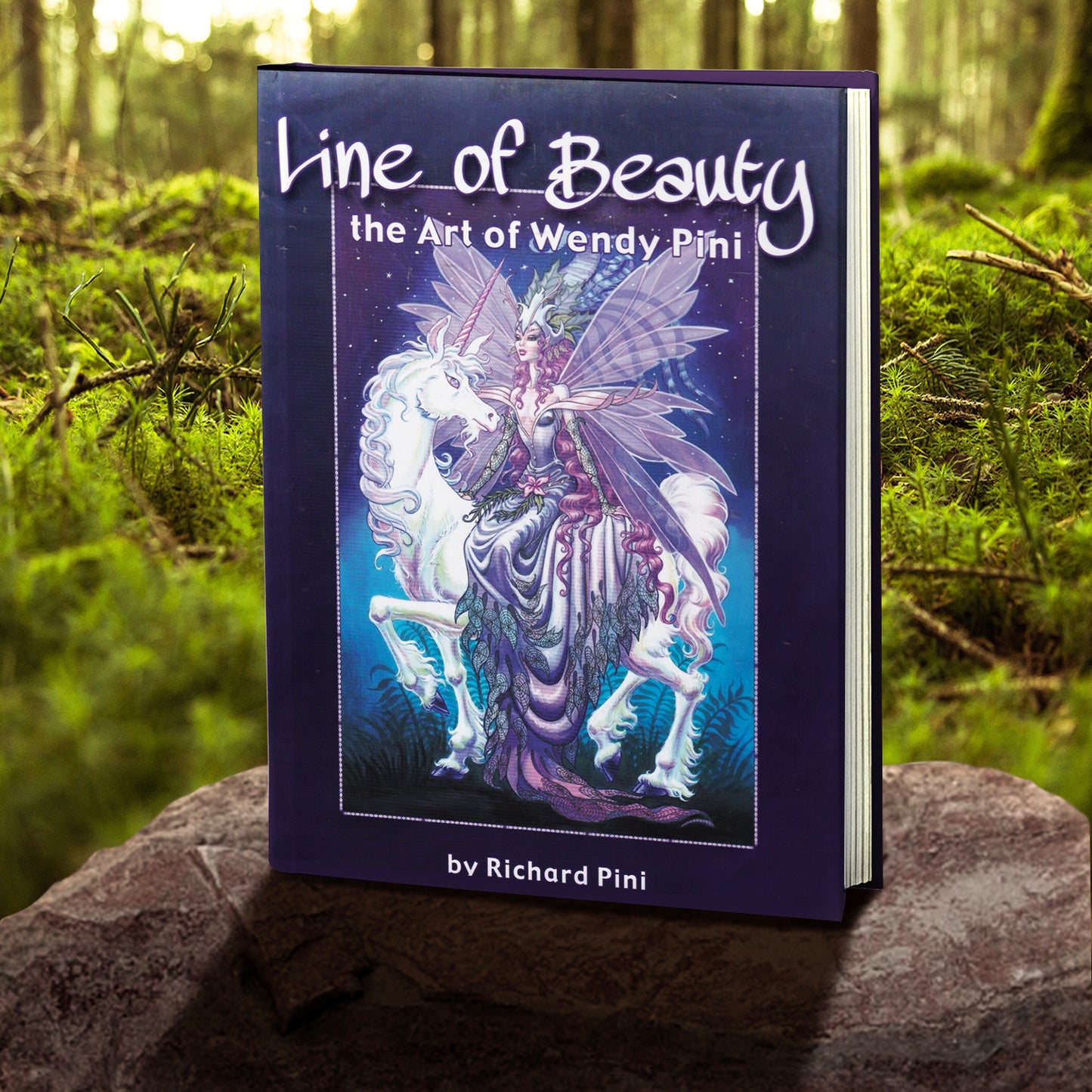 A copy of "Line of Beauty: The Art of Wendy Pini by Richard Pini" pictured in a forest. The cover is purple and features a fairy and unicorn on the front. 