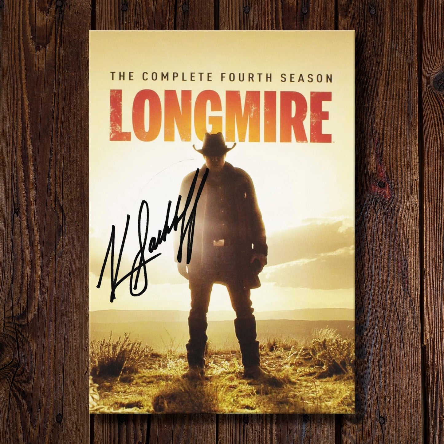 DVD cover of 'Longmire' season 4 on a wooden background. On the cover is Katee Sackhoff's autograph