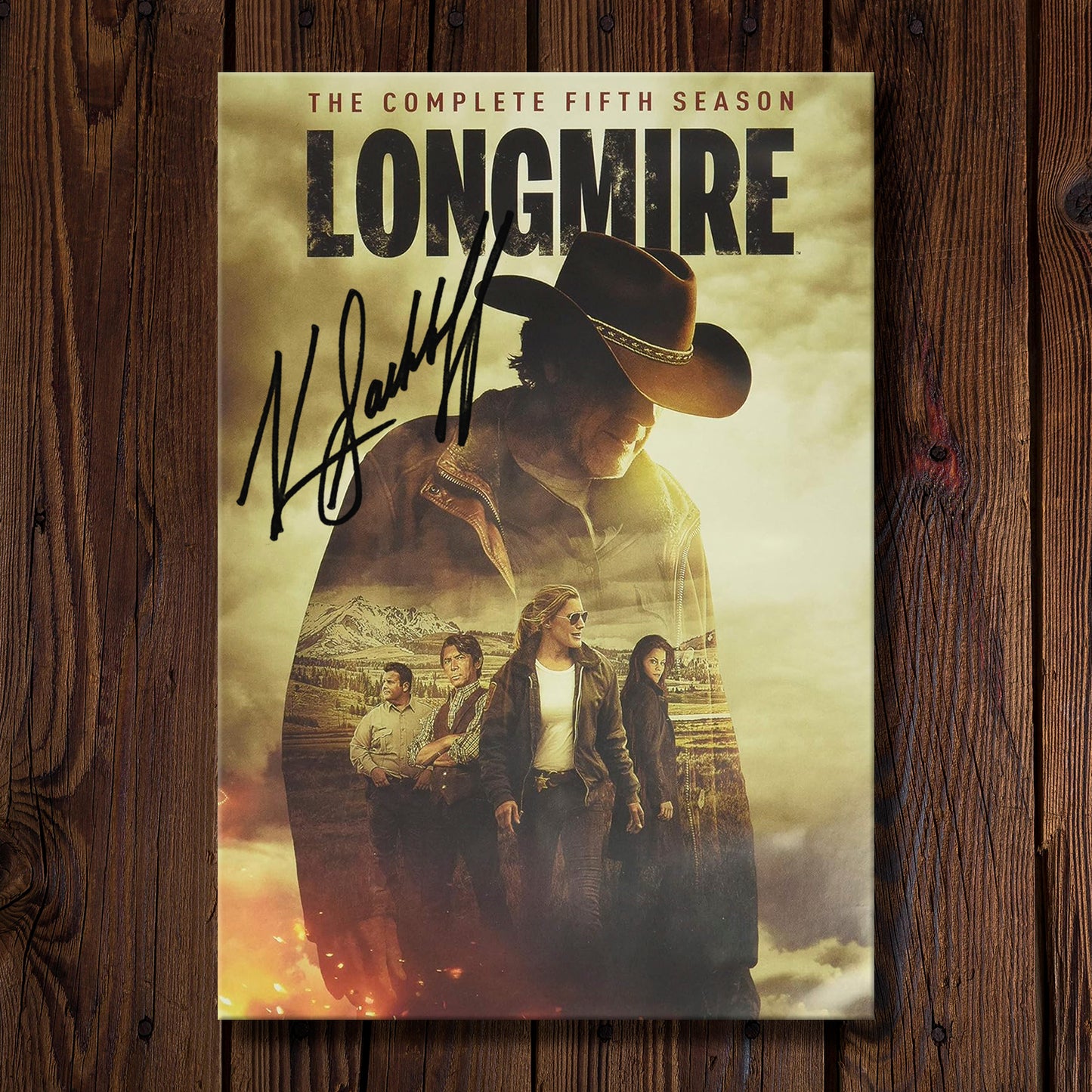 DVD cover of 'Longmire' season 5 on a wooden background. On the cover is Katee Sackhoff's autograph
