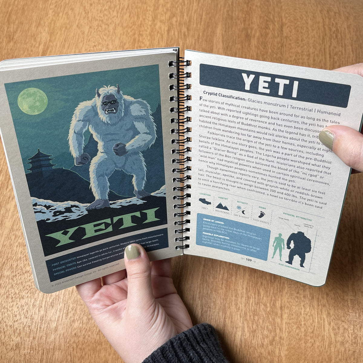 Open book showing a page about the Yeti with an illustration on a wooden surface.