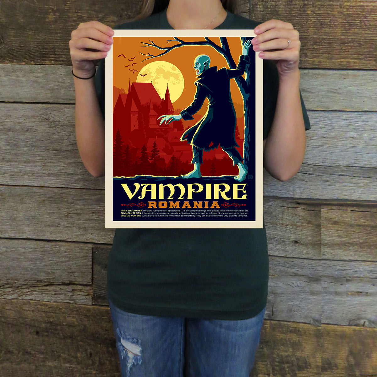 Person holding a 'Vampire Romania' poster against a wooden background