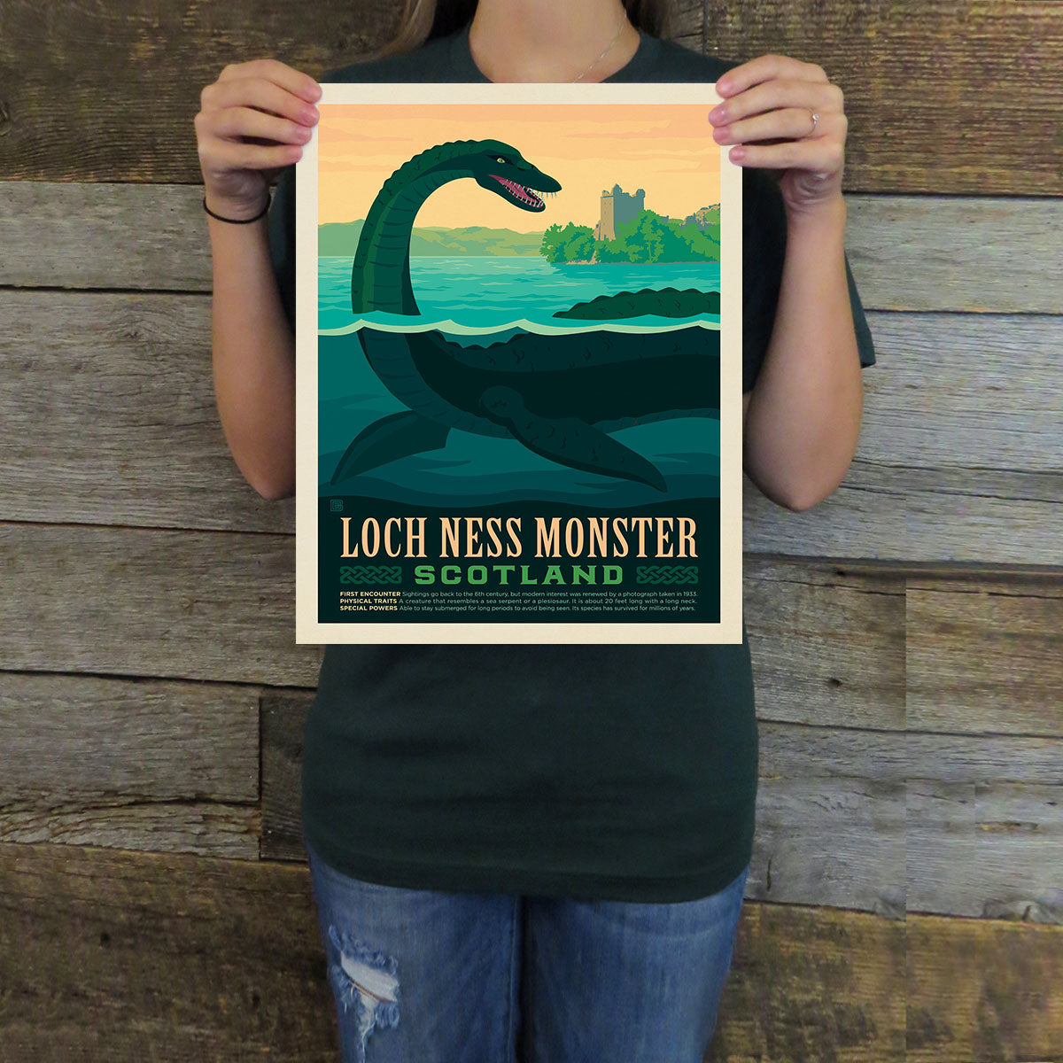 Person holding a Loch Ness Monster poster against a wooden background