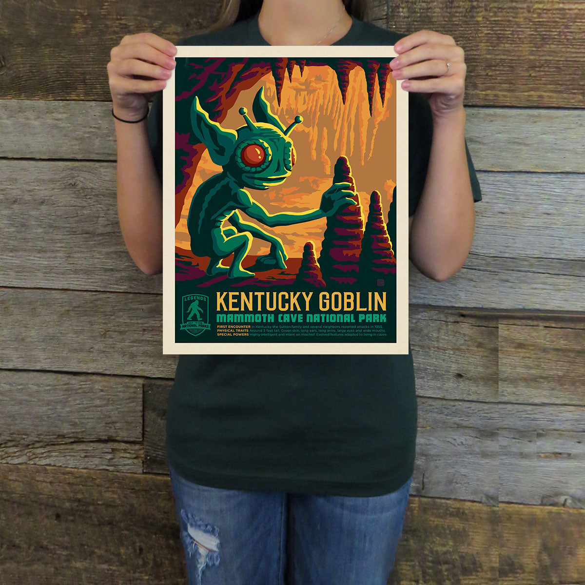 Person holding a poster of the Kentucky Goblin against a wooden background