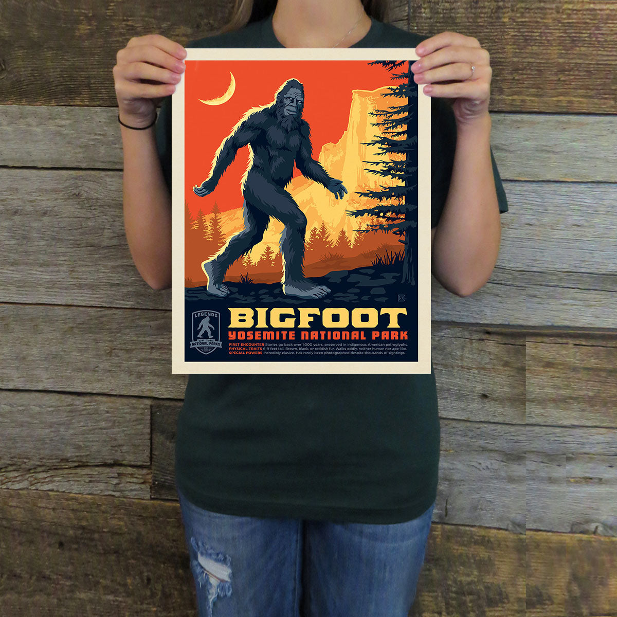 Person holding a Bigfoot Yosemite National Park poster against a wooden background