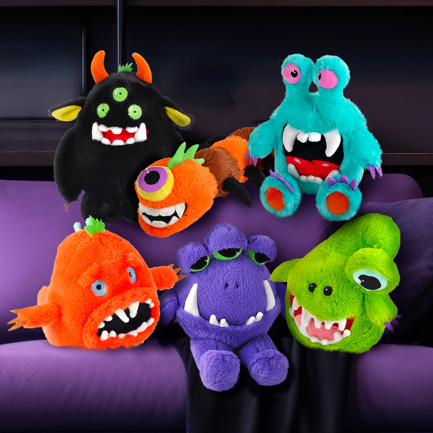 Six plushies sitting on a purple couch. One is blue with eye stalks on the top of his head. One is purple with three half-opened green eyes. One is black with three green eyes and orange horns. One is orange with a wide mouth and tentacles on its arms. One is green with fans and one giant eye on a stalk. One is orange, shaped like a caterpillar, with one purple eye.