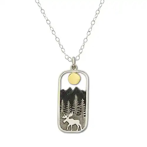 A rectangular pendant with rounded edges, against a white background. Inside the pendant is a depiction of a moose walking on front of pine trees, with mountains in the back, and a round golden sun at the top. A stainless steel necklace chain is attached to the pendant.