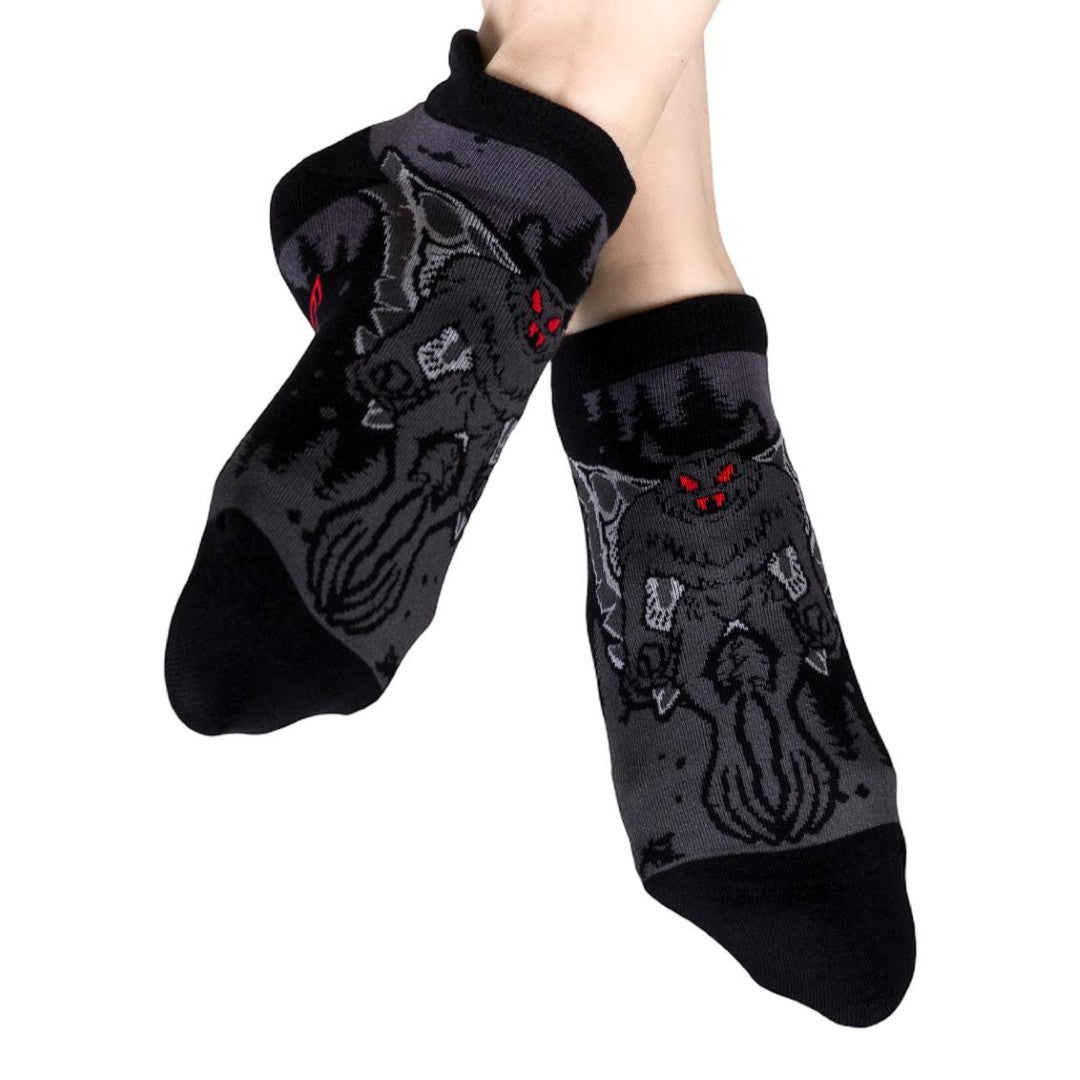 Black socks with Mothman designs worn by a person on a white background