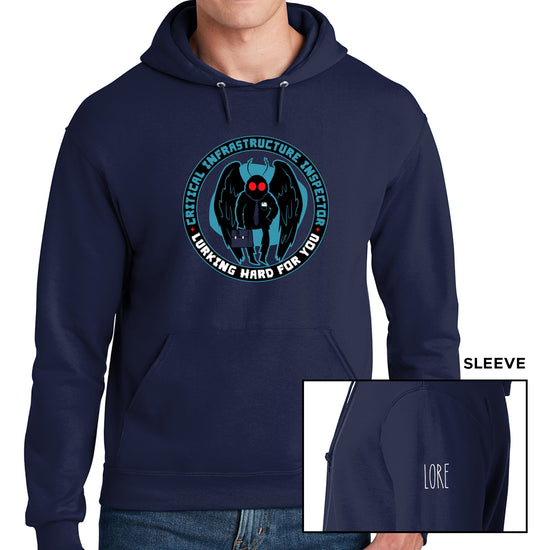 A male model wearing a navy hoodie with matching drawstrings and a kangaroo style pocket. The tee has a black ring/circle printed with the words "Critical infrastructure inspector" in dark blue font and "Working hard for you" in white font. Within the ring is a black cartoon Mothman with red eyes, a navy tie, and a navy briefcase set against a lighter shadow. One sleeve features the 'LORE' logo in white. 