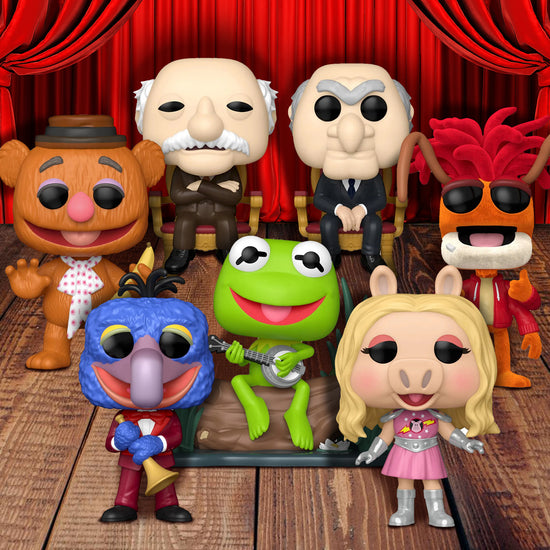 A collection of Funko Pop! figures depicting different Muppets, on a wooden floor. In the background is a red theater curtain.